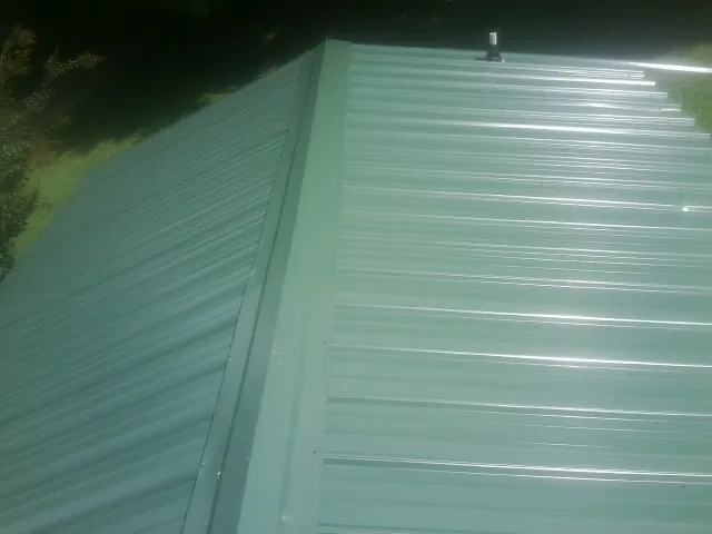 New green metal panels meeting at the ridge of a roof — Flat Roof Repair work by our crew in Port Royal